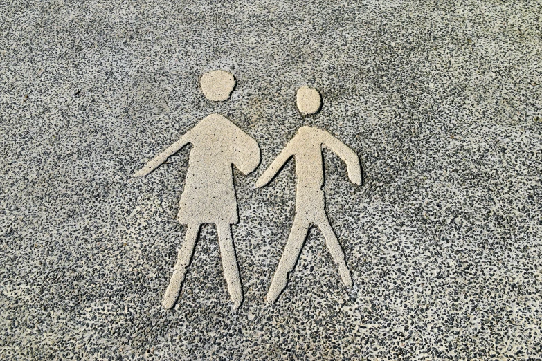a drawing on the sand depicts two people holding hands