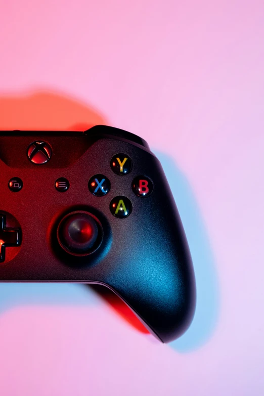 a controller with ons sits in front of a pink background
