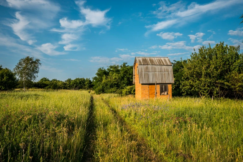 an old red building in the middle of a field