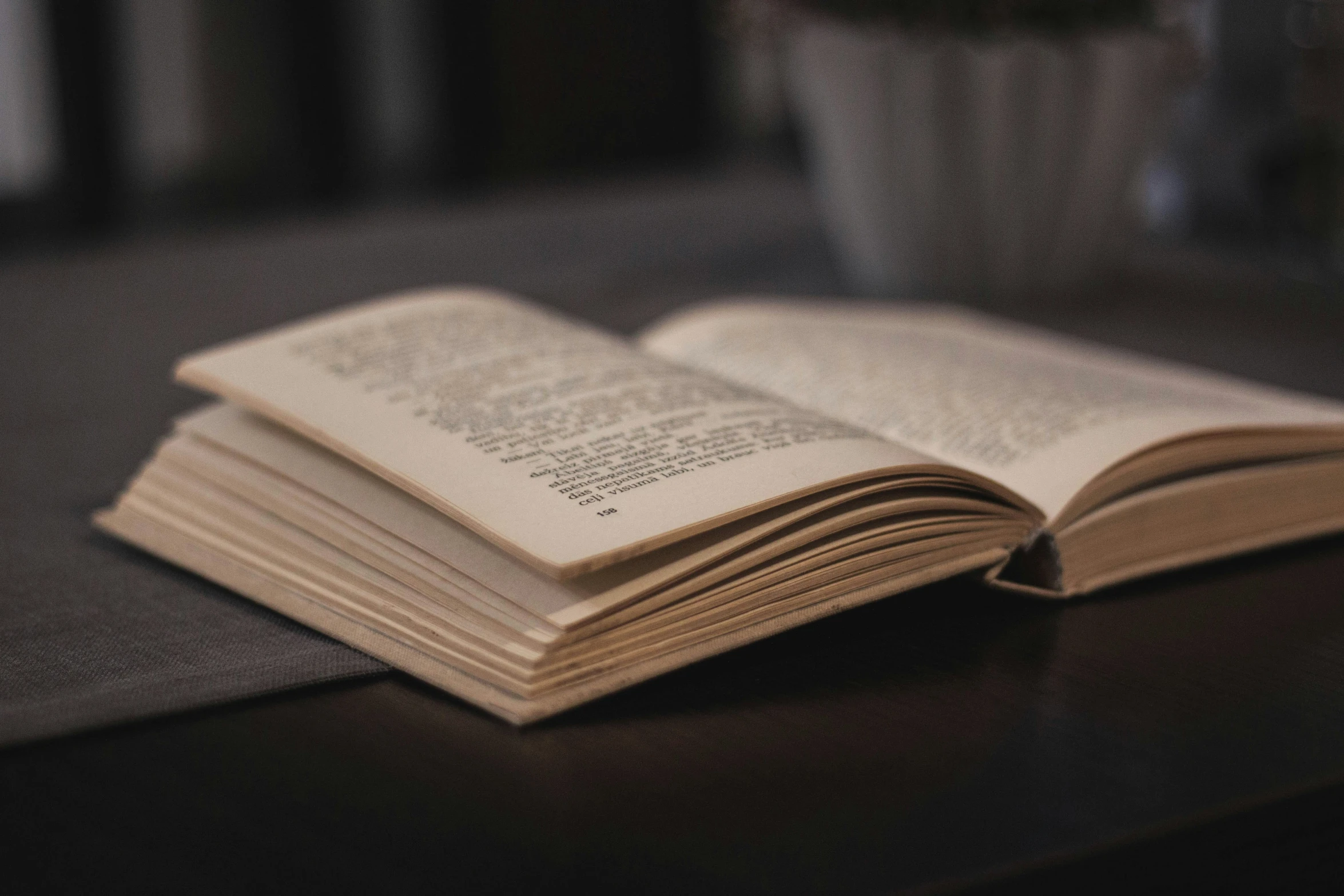 an open book sitting on a black table with some coffee cups