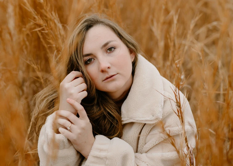 the woman is posing in tall grass for the picture