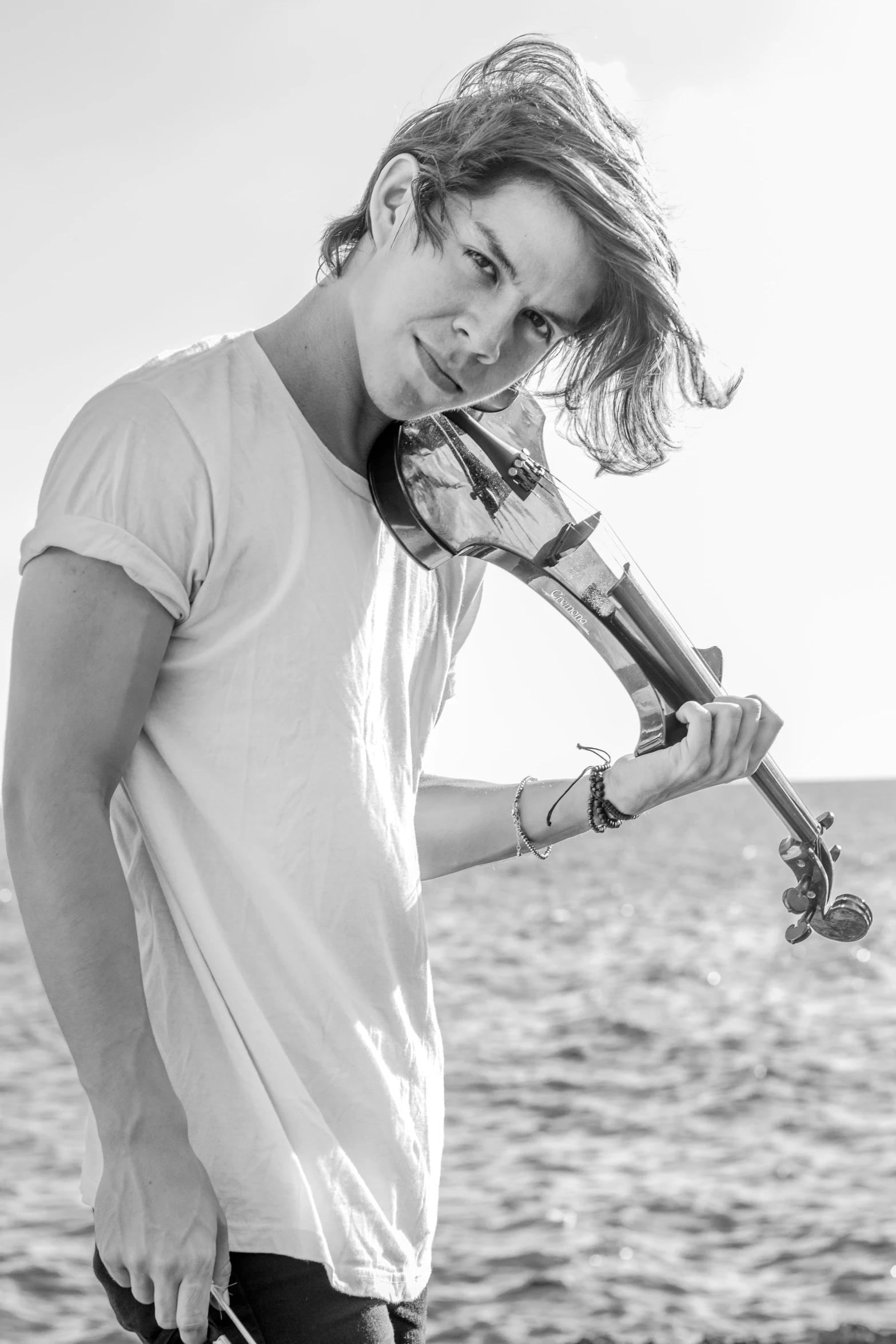 a man holds a violin on the shore