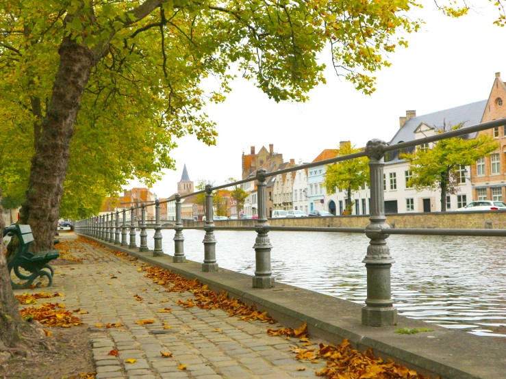 a bench is set next to a canal with houses lining it