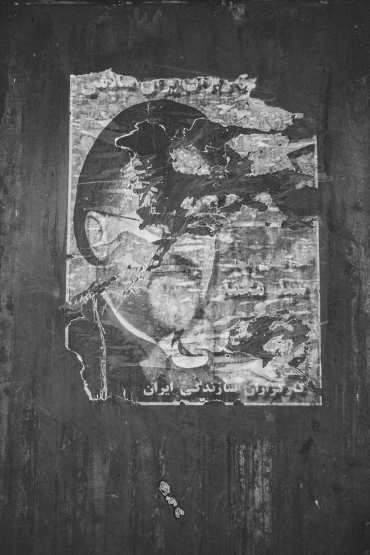 the black and white picture shows the silhouette of a face on a piece of wood