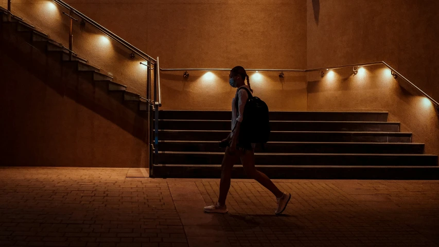 a woman walking down the street by stairs lit with lights