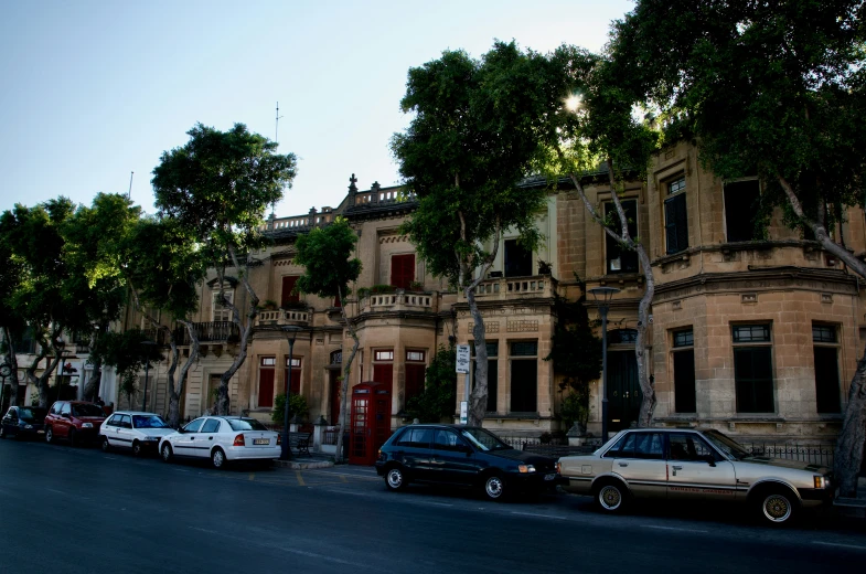 several parked cars line the street near an old house