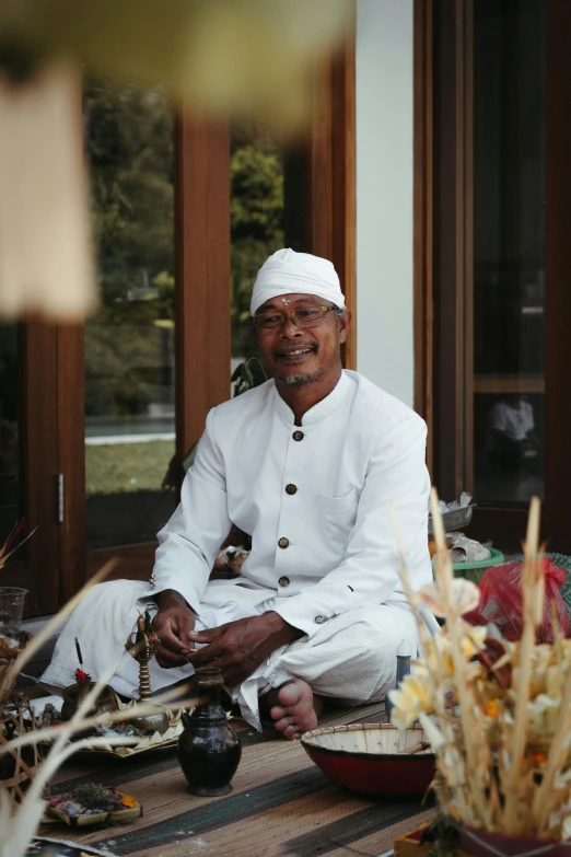 a smiling man sitting on top of a wooden table