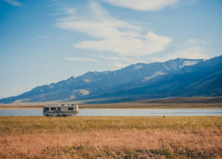 rv parked in the field and mountains by the lake