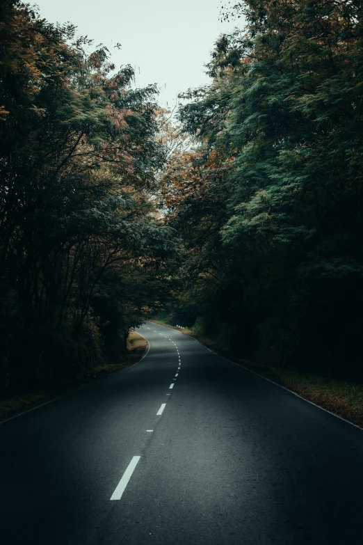 a dark and empty road with only one car driving on it