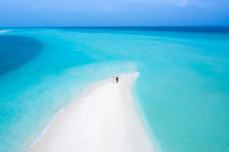 two people walk on an almost empty beach