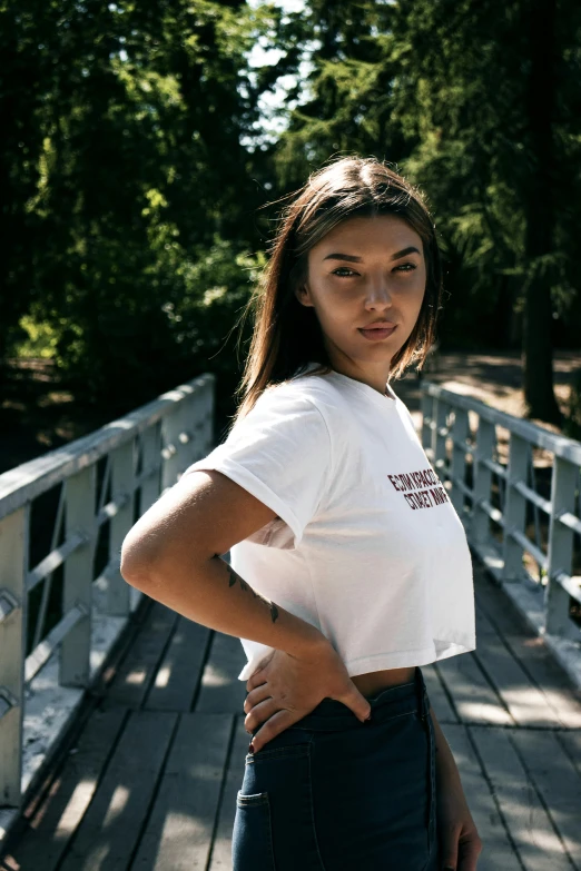 a woman in a white shirt and jeans poses for a po on a bridge