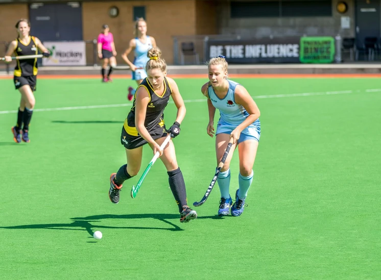 two girls playing field hockey in front of a building