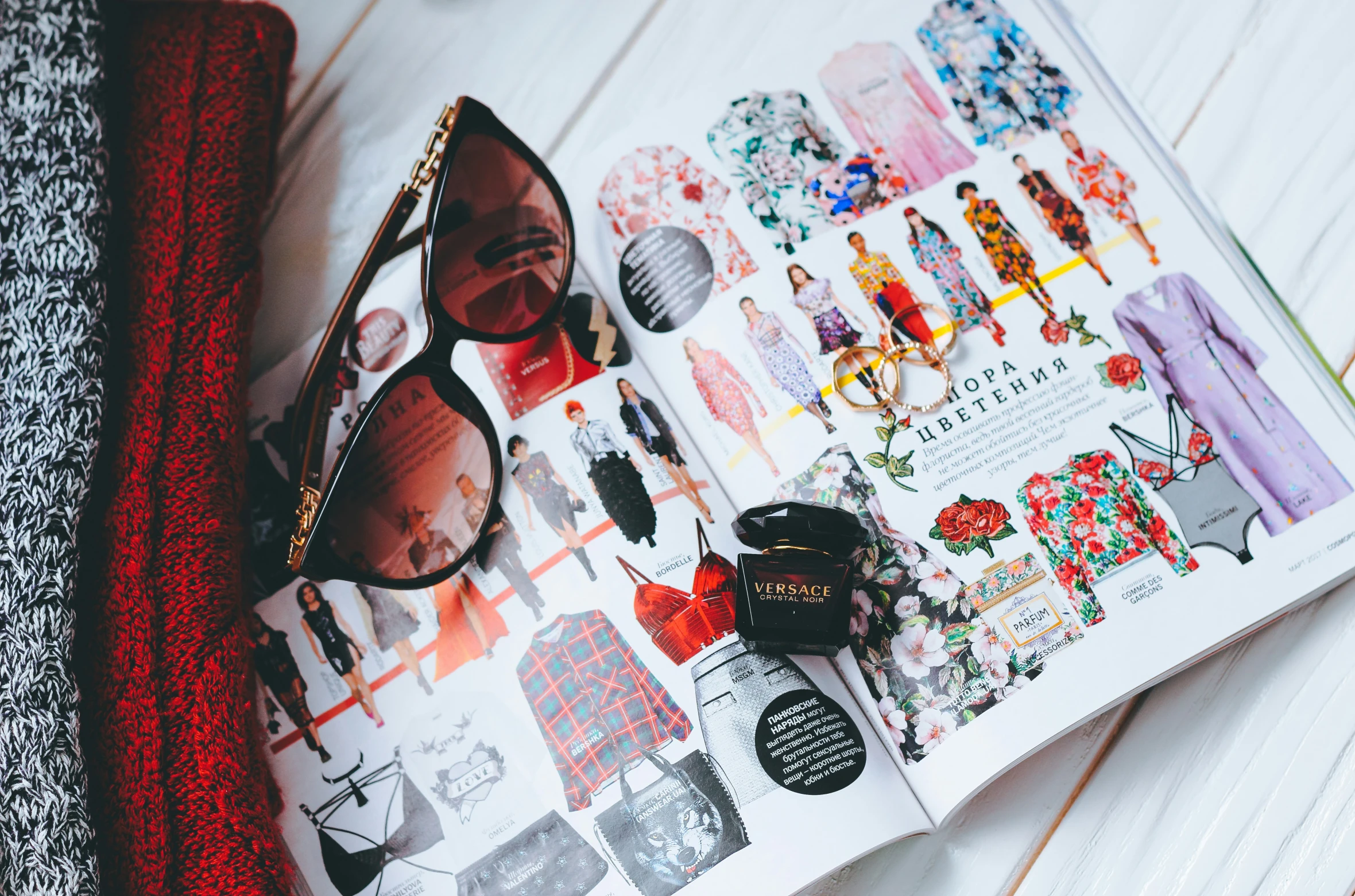 there are sunglasses, eyeglasses and a magazine laying on a bed