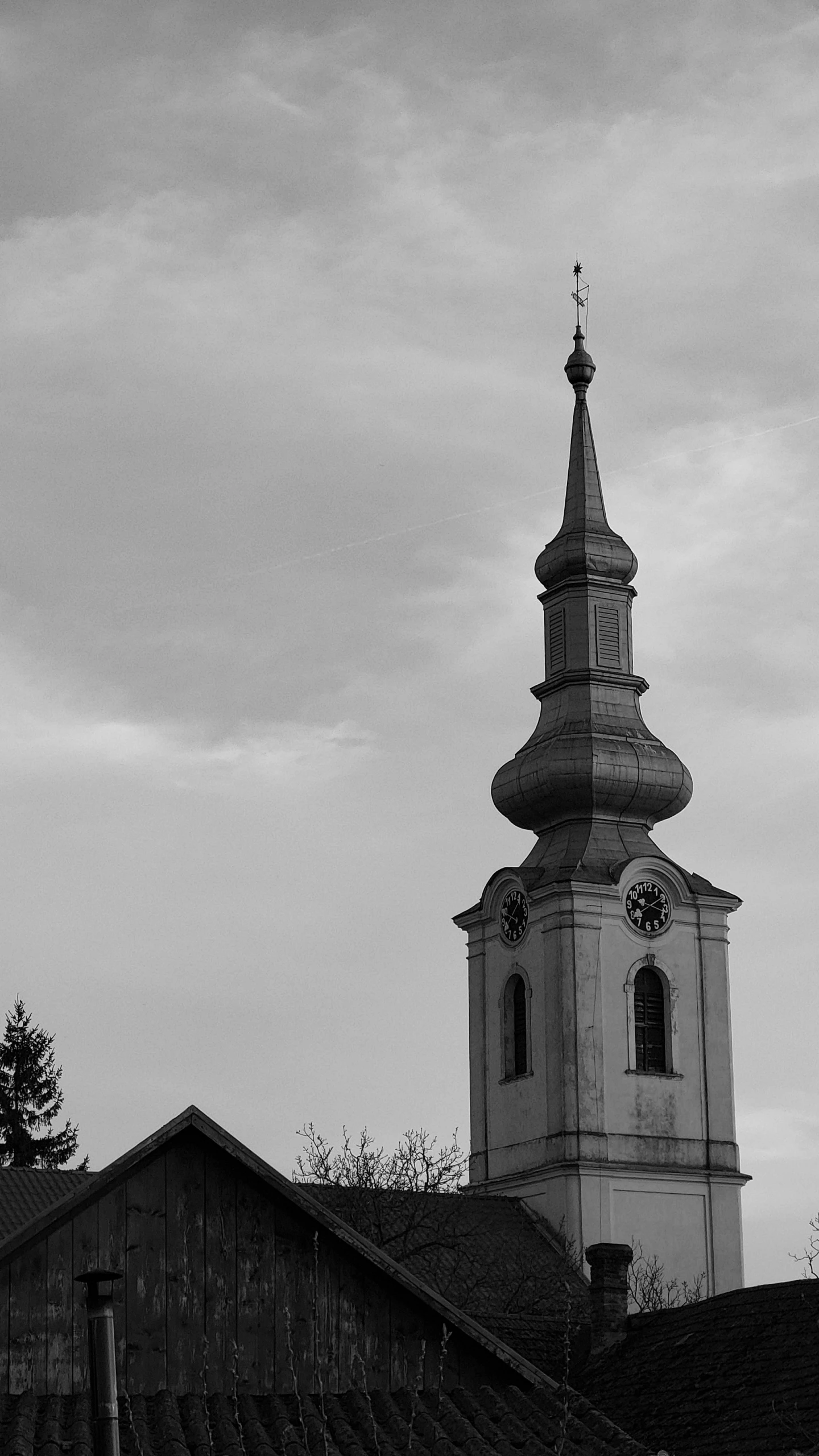 a large clock tower rises in the sky above rooftops