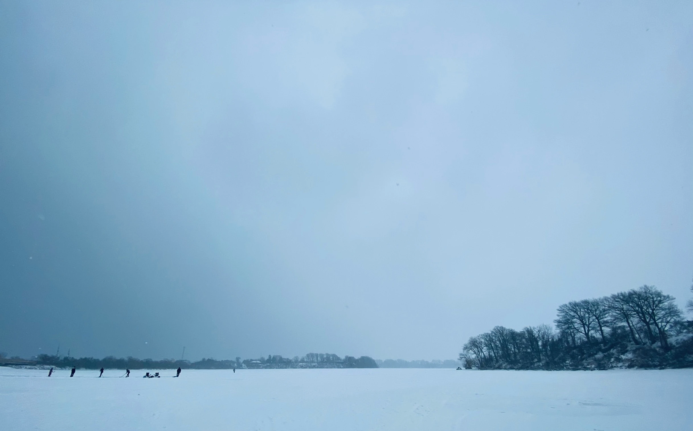 a couple of people walking across a snow covered field