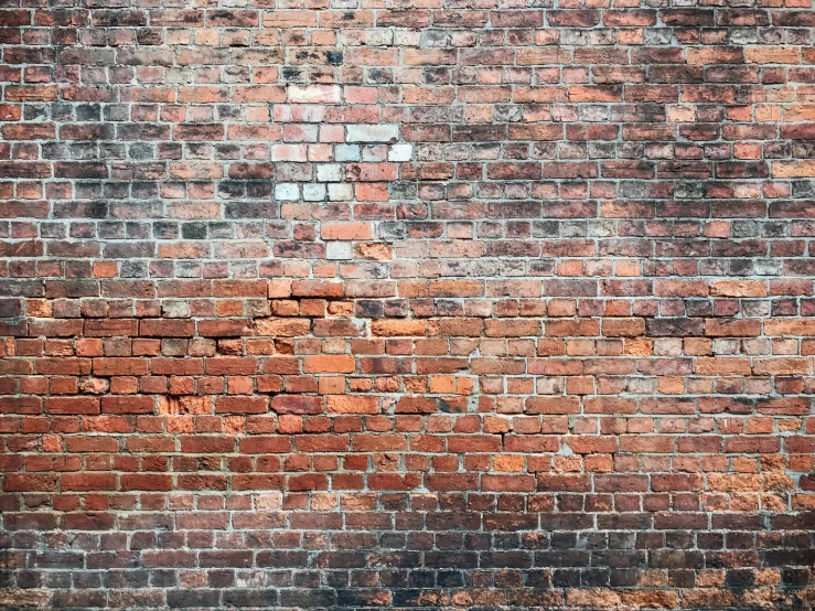 a red and black fire hydrant sitting by a brick wall