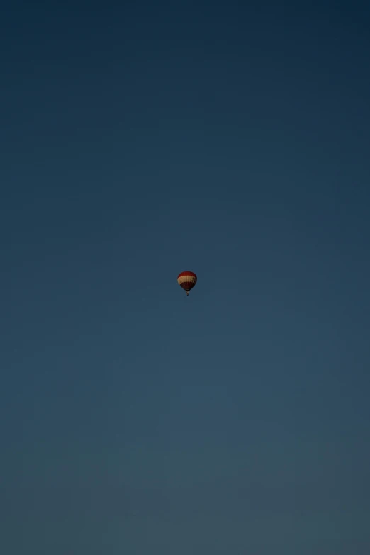 a small balloon flying across a blue sky