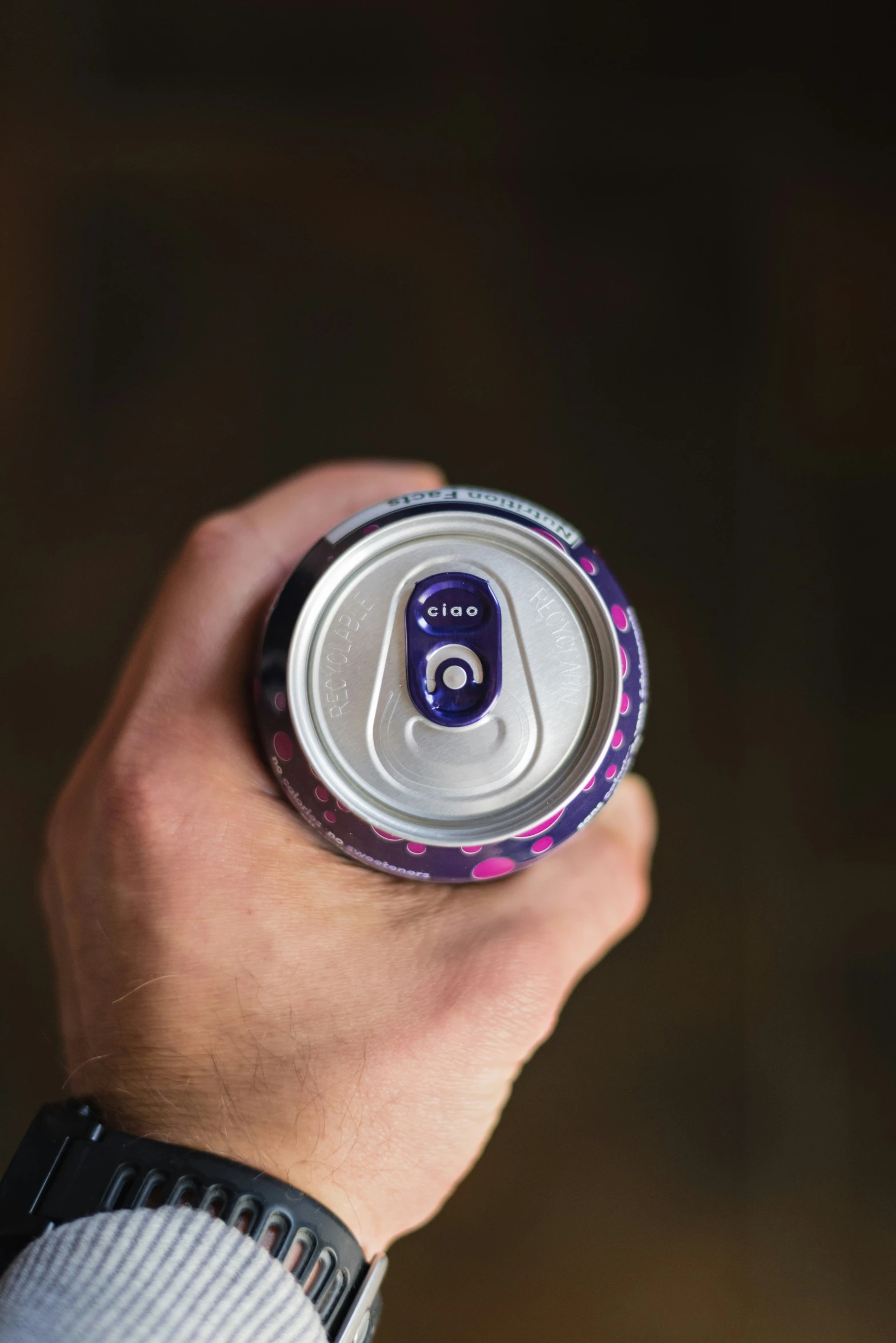 man's hand holding and holding up the top of a soda can