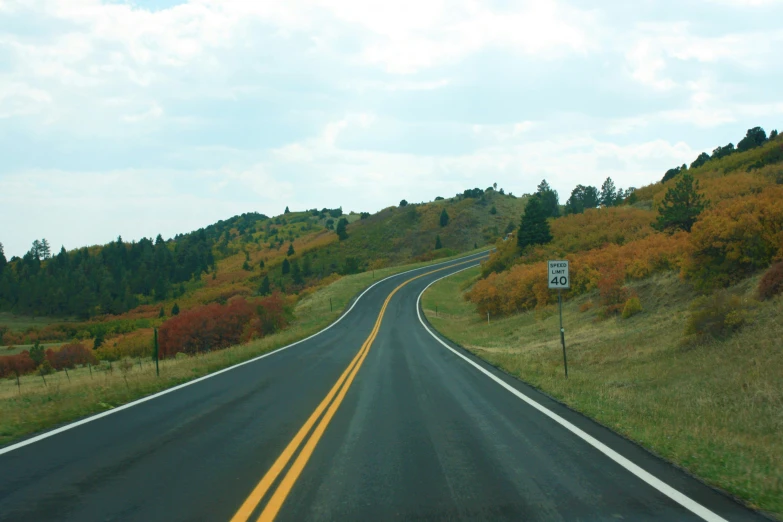 a road with three different lines in it and trees in the distance