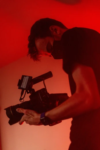 two people in silhouette behind a camera with red lights