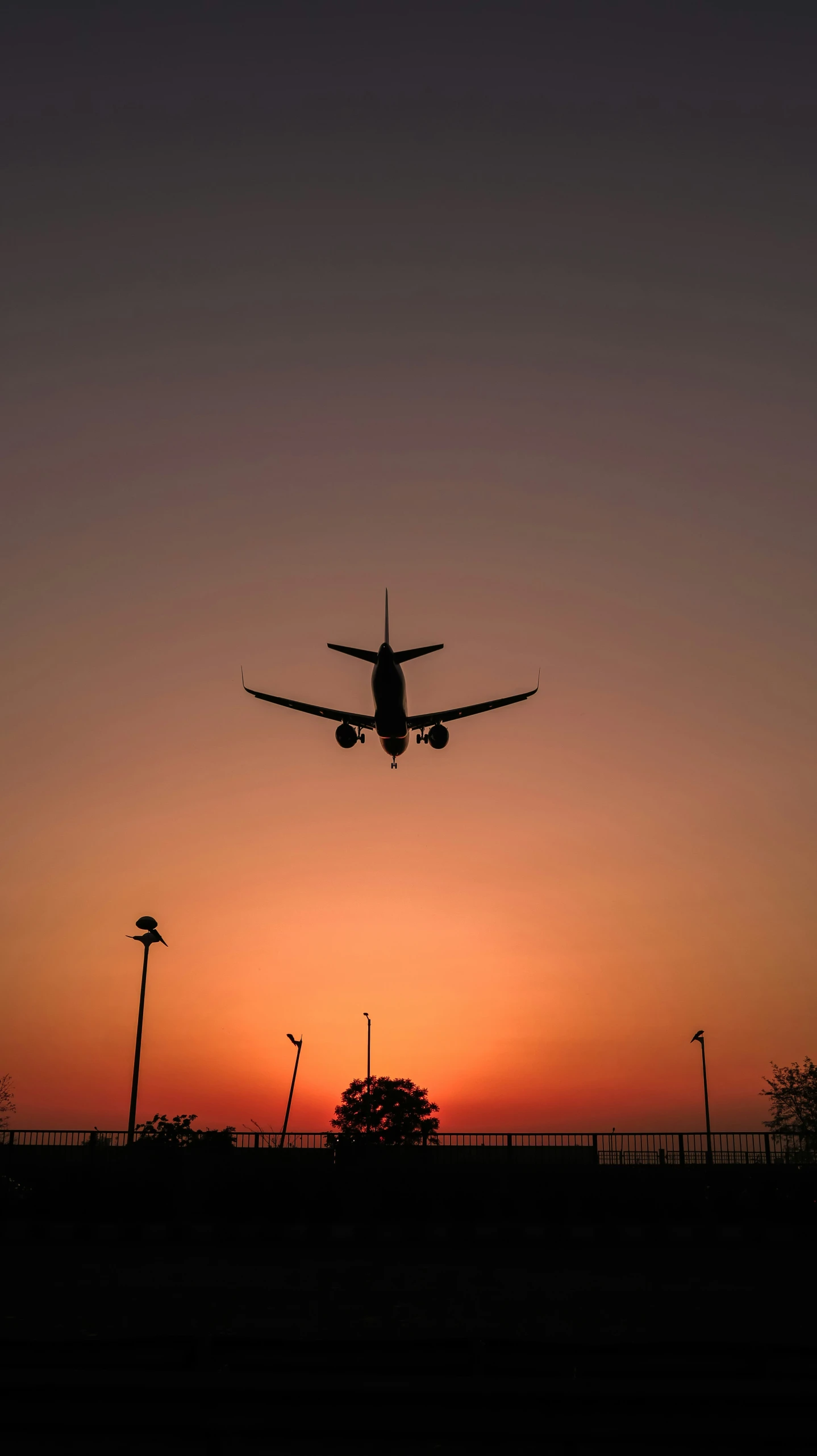 the silhouette of a large airplane flying in a sunset