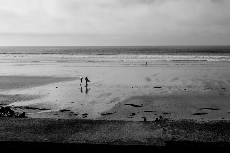 two people walking on the beach with a kite