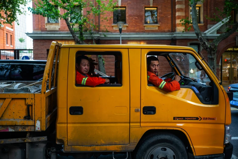 two men sitting in a truck near a building