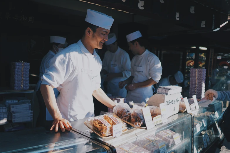 a chef putting food in a buffet behind a glass counter