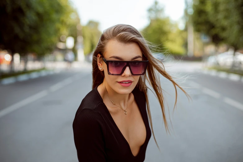 a girl in sunglasses standing on the side of the road