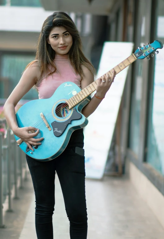 a woman holding a blue guitar while posing