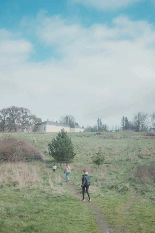 two people are in a field, one is flying a kite