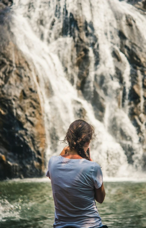 the woman is looking at a waterfall while talking on the phone