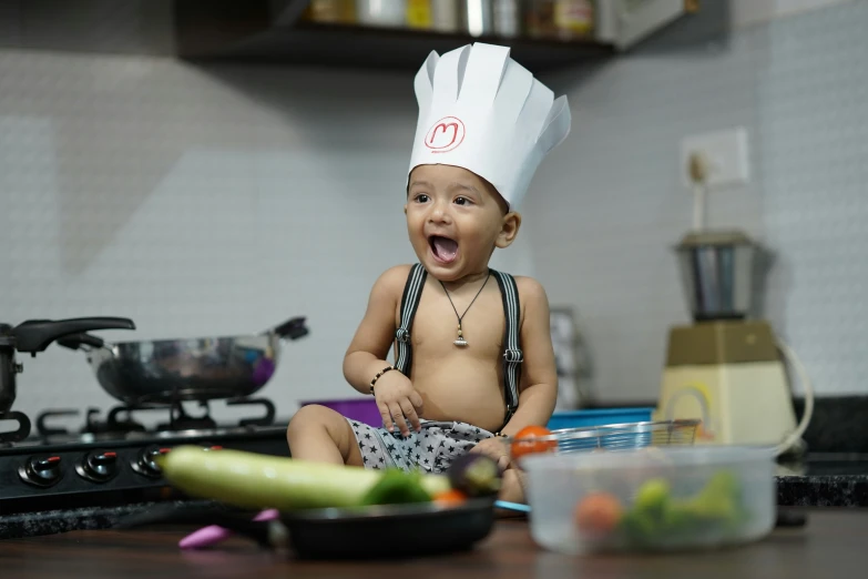 small baby in a chefs hat sitting on the table