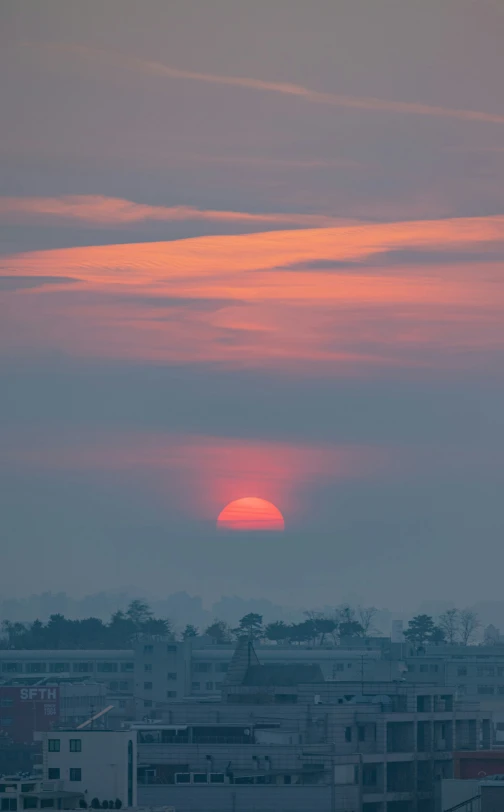 a very large beautiful orange sun with some clouds