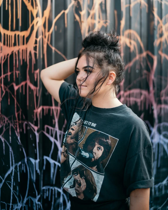 woman in black shirt standing next to graffiti covered wall