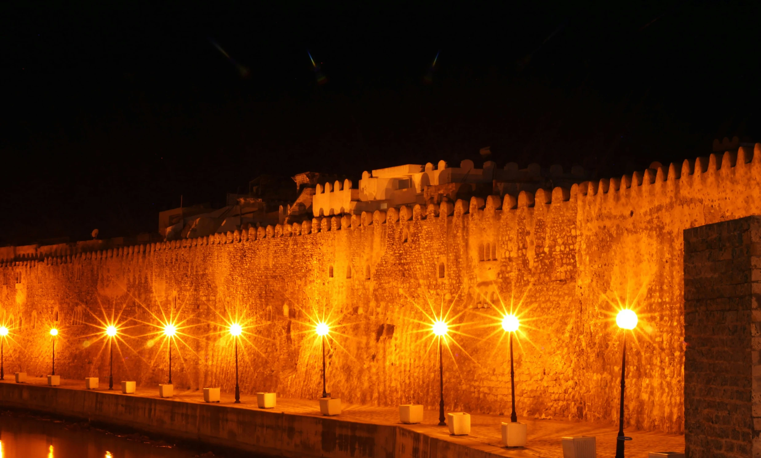 a stone castle at night with lights around