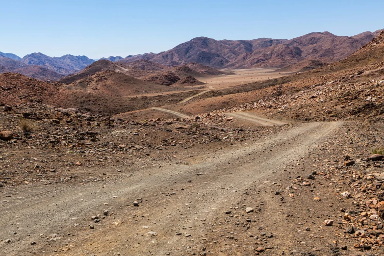 a dirt road winding through the barren mountainous terrain