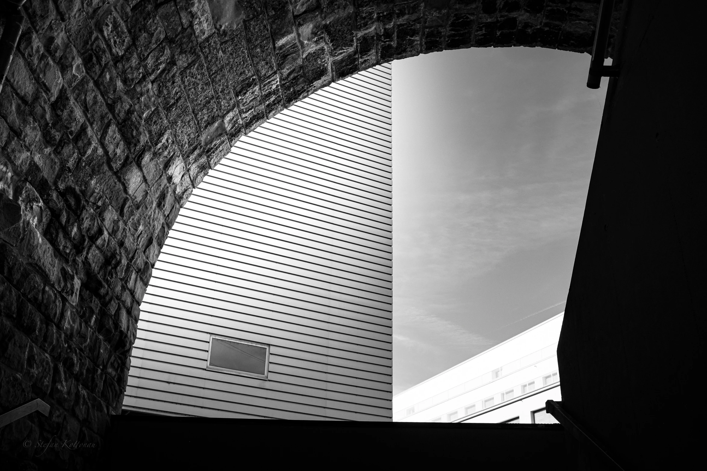 a stone arch next to a building with a clock