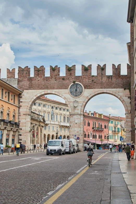 a motorcycle on the road is driving under a brick archway