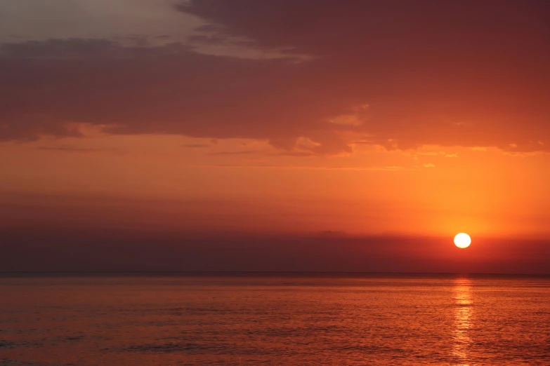 a body of water with the sun in the background