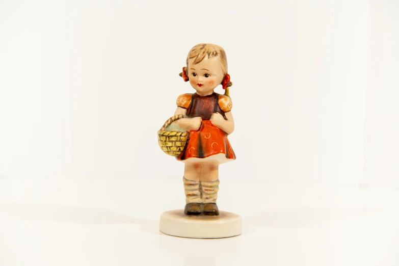 small ceramic girl figure on white background carrying a basket