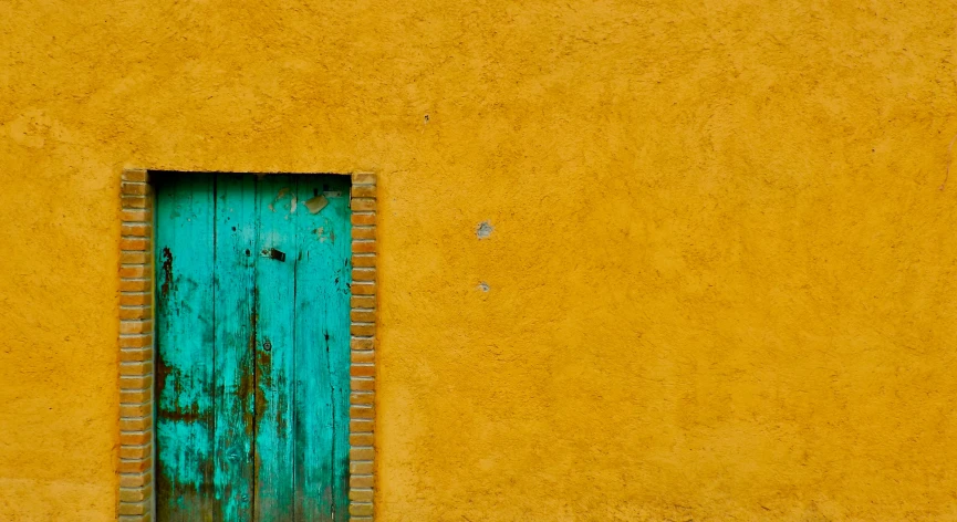 a painted door and window in an old yellow wall