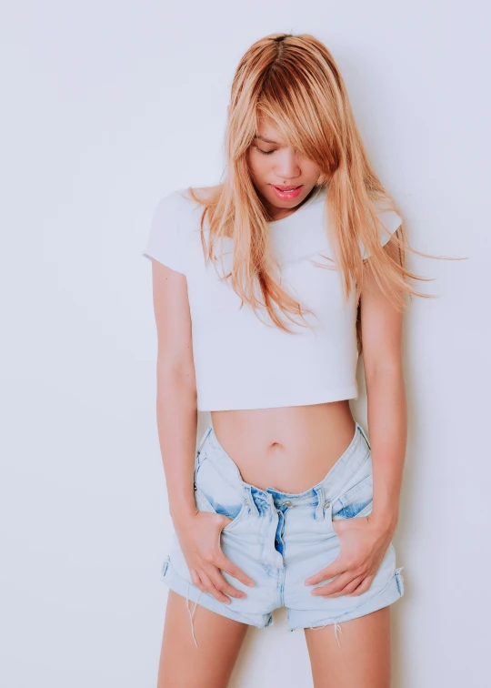 a woman in blue shorts standing next to a white wall