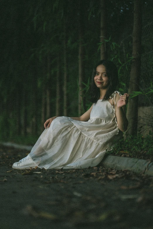 a woman in white is sitting down on the ground