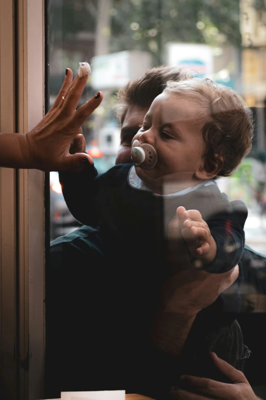 a young child holds a pacifier in a city shop