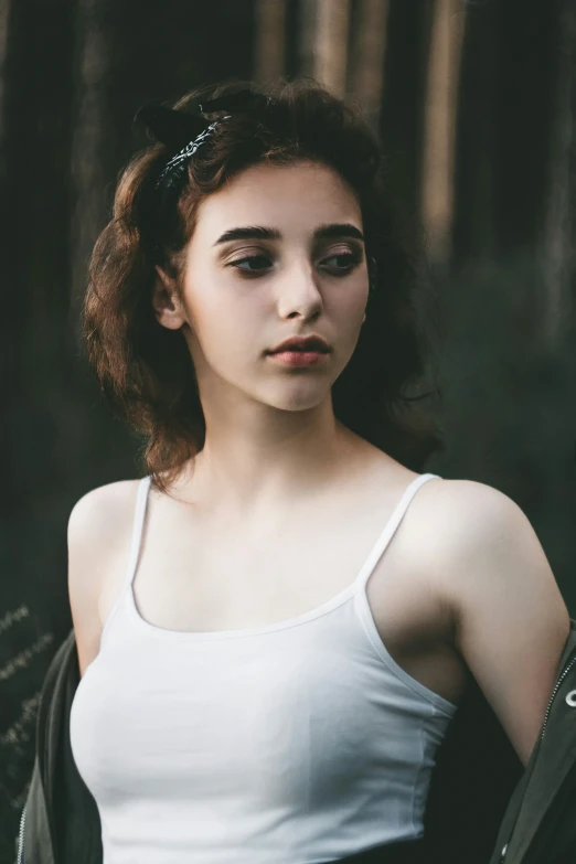 a woman with brown hair is wearing a white tank top