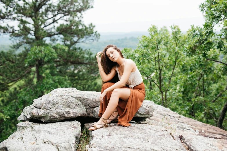 a woman is sitting on top of a rock