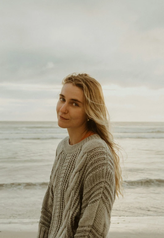 a woman stands at the beach with her hair blowing in the wind