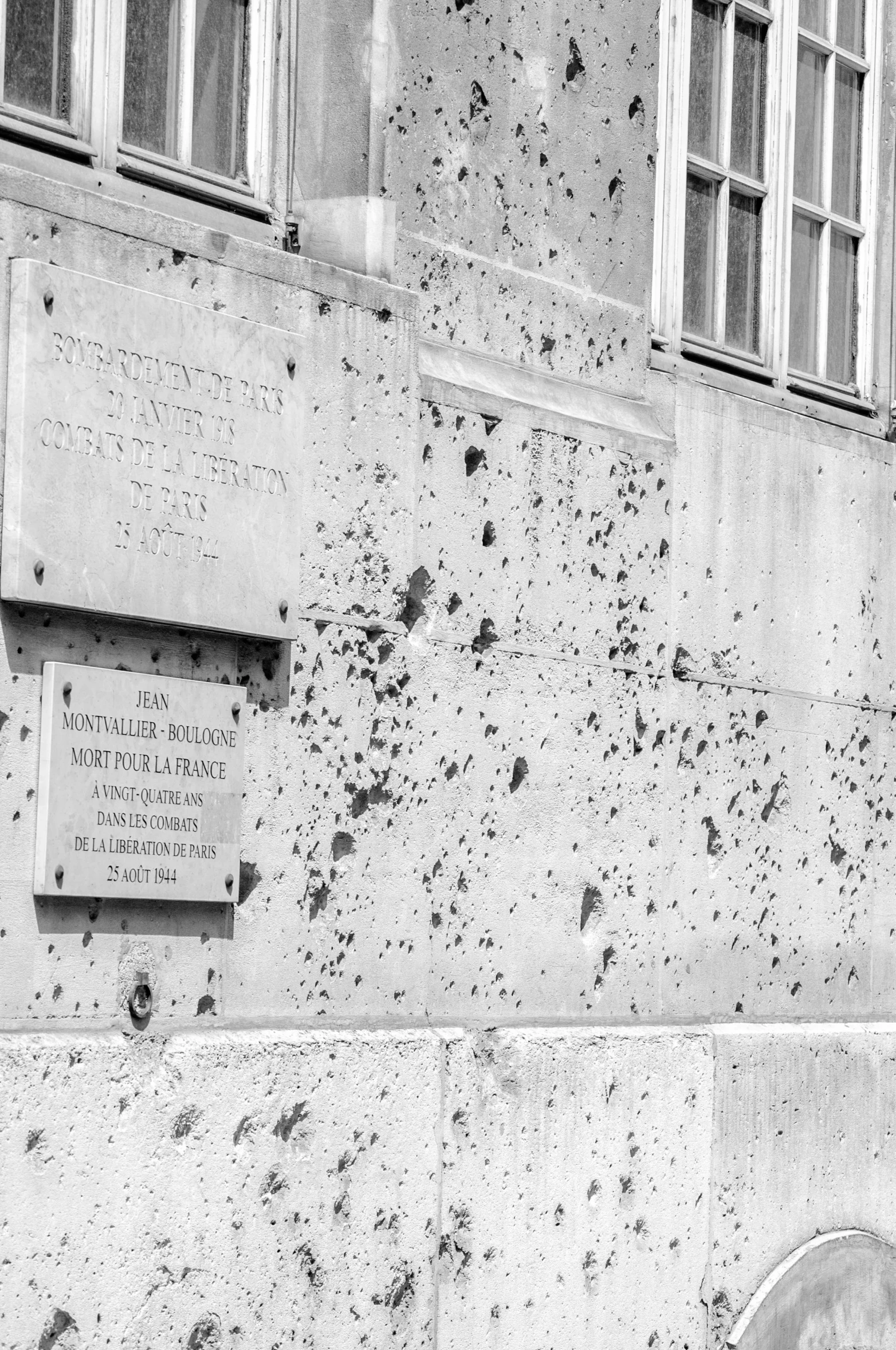 a black and white picture of a wall with bullet holes