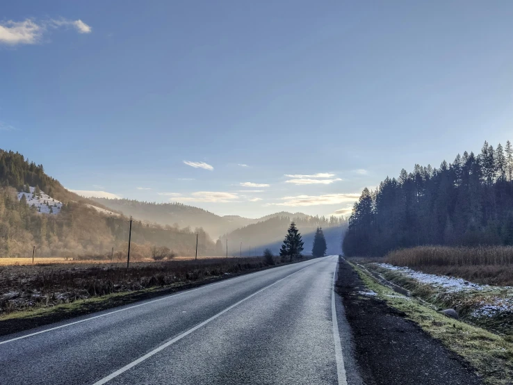 a country road in the mountains, with the snow on the ground and tall trees